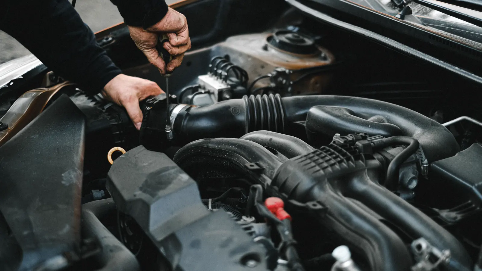Hands working on components in a vehicle engine bay