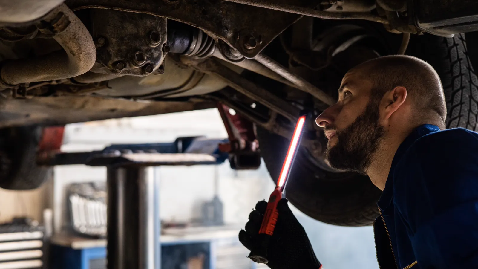 Technician inspecting a CV axle boot near a vehicle wheel