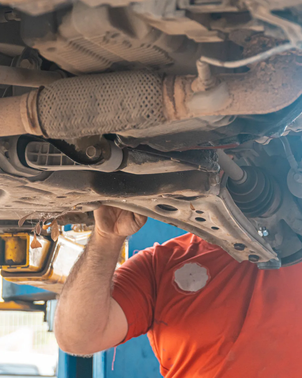 Technician inspecting components beneath a raised vehicle
