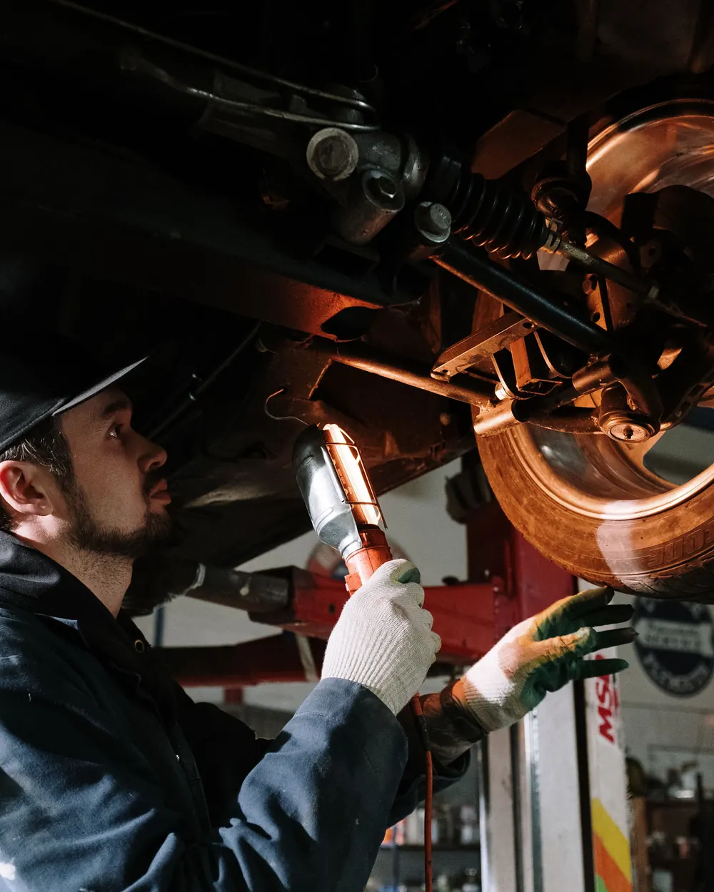 Mechanic using a work light to inspect vehicle components