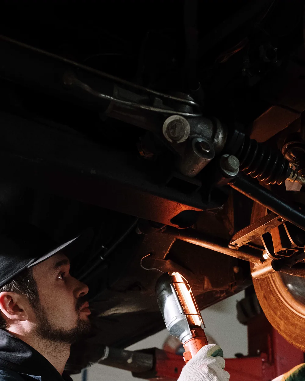 Mechanic using a work light to examine suspension components