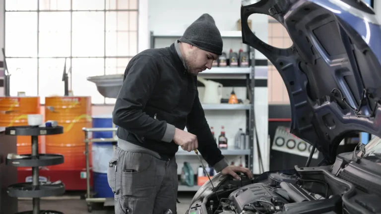 Technician inspecting a car engine under an open hood in a garage