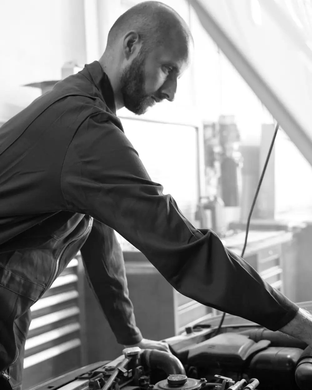 Mechanic leaning over an open engine bay during a vehicle inspection