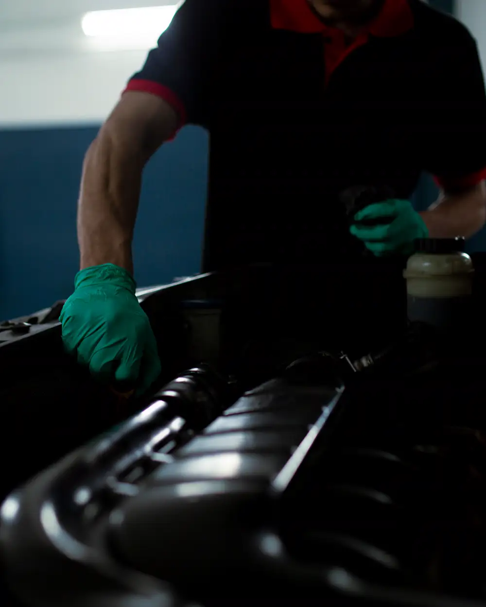 Gloved technician inspecting components in an open vehicle engine bay