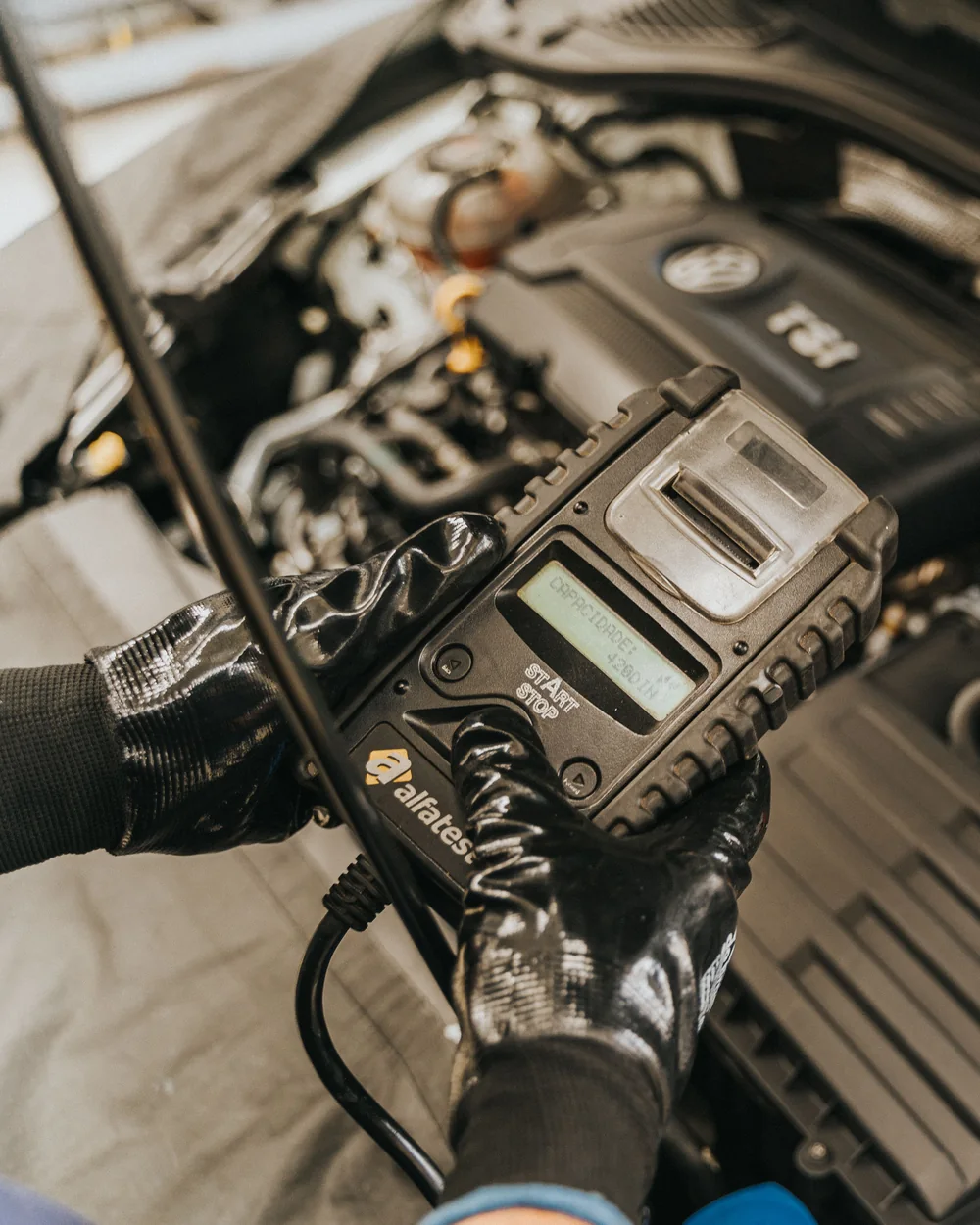 Technician using a diagnostic tool under a car hood
