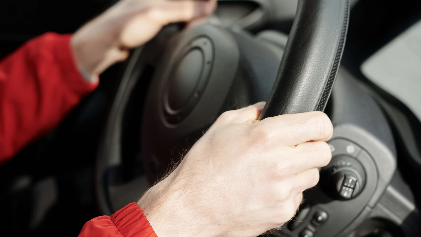 Hands on a steering wheel inside a car