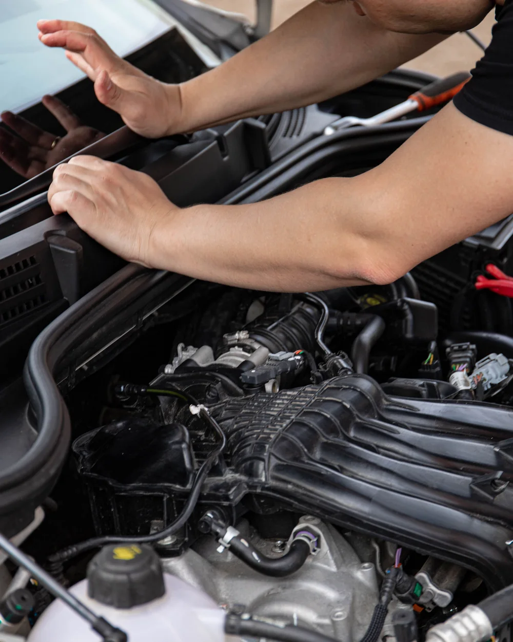 Technician leaning over an open engine bay during a visual inspection