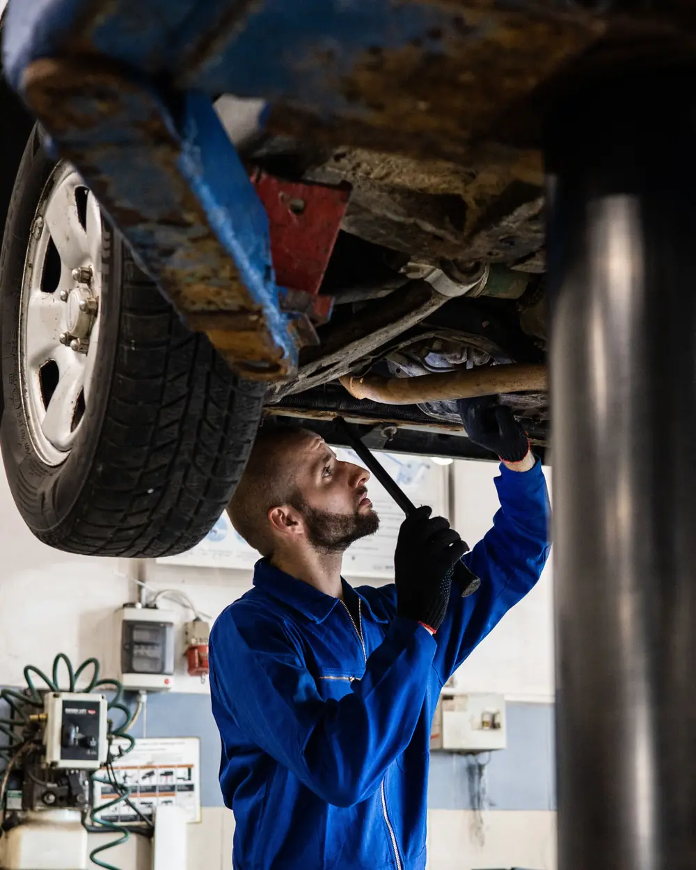 Technician inspecting a vehicle undercarriage on a hydraulic lift