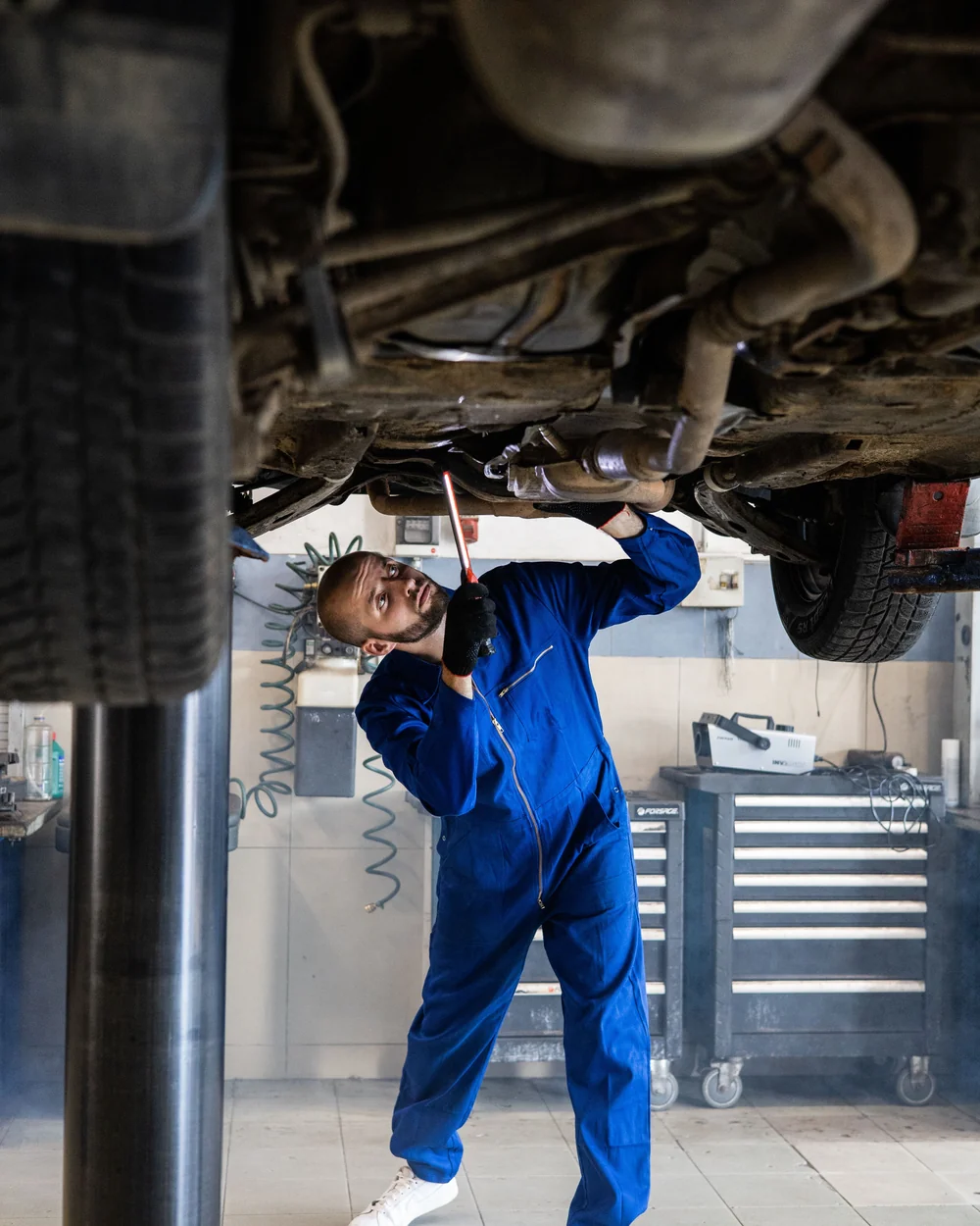 Technician inspecting the underside of a car on a workshop lift