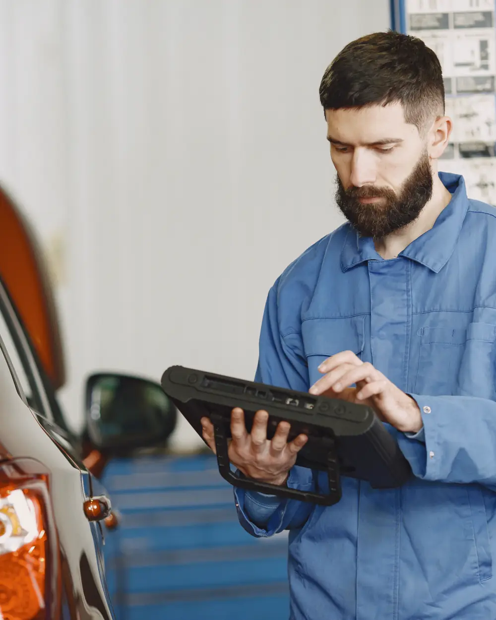  Technician using a diagnostic device in an automotive workshop