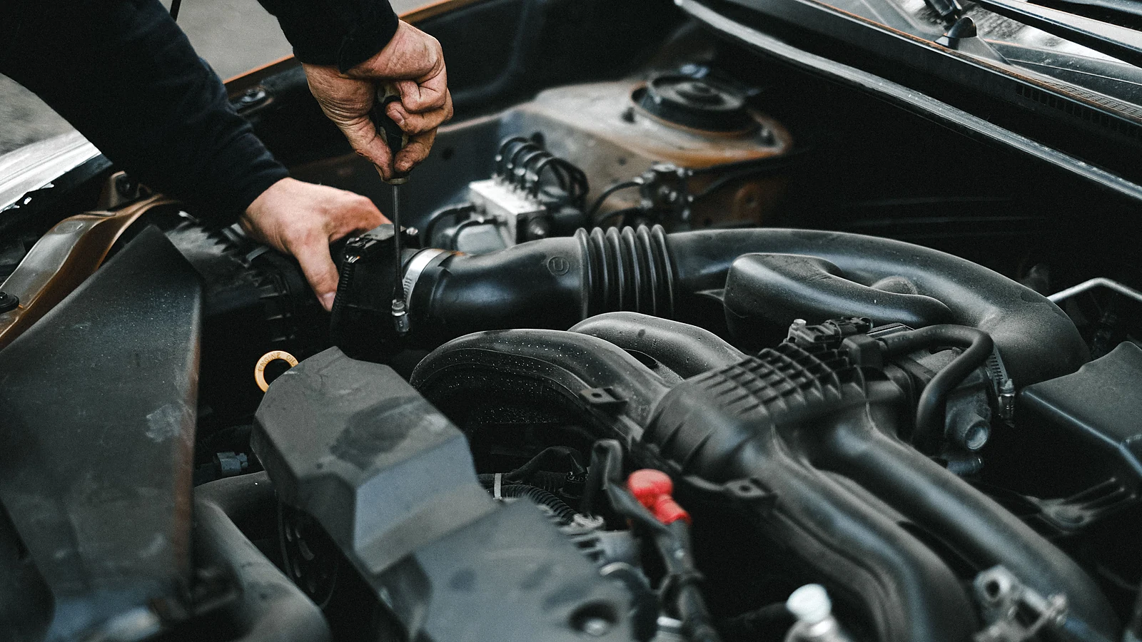 Mechanic inspecting a vehicle engine with the hood open